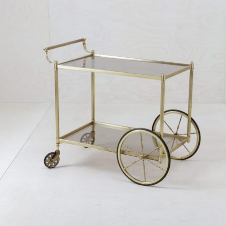 Bar Trolley Agatha | The Agatha bar trolley has an elegant, golden frame. We rent the golden trolley together with two corresponding glass shelves. The bar trolleys are ideal for small decorations, for presenting selected goods or very traditionally, for a whisky glass carafe and chic lead crystal glasses. | gotvintage Rental & Event Design