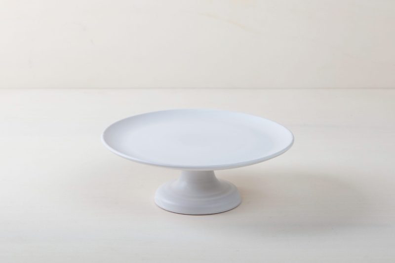  | Our small elevated round cake stand Ernesta rests on a 12 cm high foot and has a diameter of 32 cm. Space to present and serve cakes, cupcakes, sushi and other delicious food on the table or at the modern buffet. The serving trays are handcrafted from high-quality terracotta and glazed matt white, of course food safe.
These cake stands are available in three different sizes as well as a matt black serving plate. They can be wonderfully combined for presentations. | 