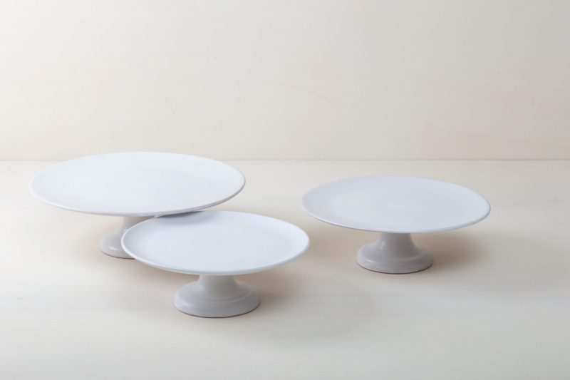  | Our large round elevated cake stand Ernesta rests on a 15 cm high foot and has a diameter of 40 cm. Enough space to present and serve cakes, cupcakes, sushi and other delicious food on the table or at the modern buffet. The serving trays are handcrafted from high-quality terracotta and glazed matt white, of course food safe.
These cake stands are available in three different sizes as well as a matt black serving plate. They can be wonderfully combined for presentations. | 